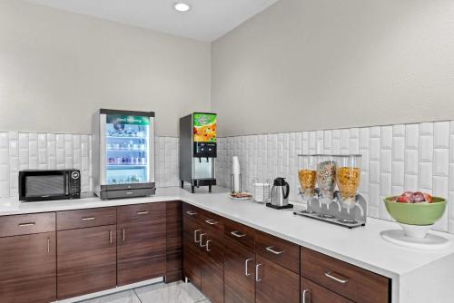 a kitchen with wooden cabinets and a microwave and a counter at Quality Inn & Suites Sunport Airport Albuquerque in Albuquerque