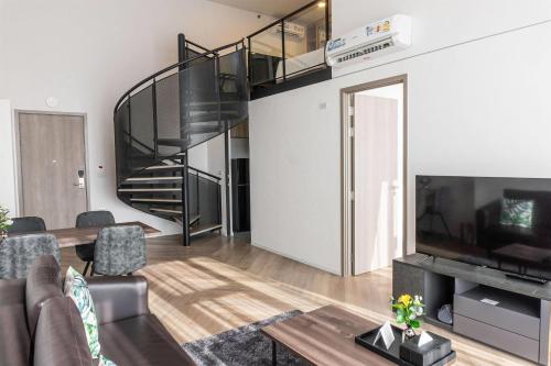 a living room with a spiral staircase in a loft at Ramada By Wyndham Bangkok Sukhumvit 87 in Bangkok