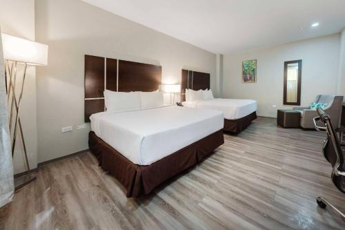 a hotel room with two beds and a couch at Comfort Inn & Suites Tobago in Tobago Island