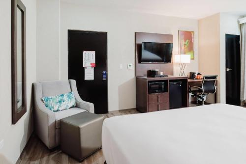 a hotel room with a bed and a chair and a television at Comfort Inn & Suites Tobago in Tobago Island
