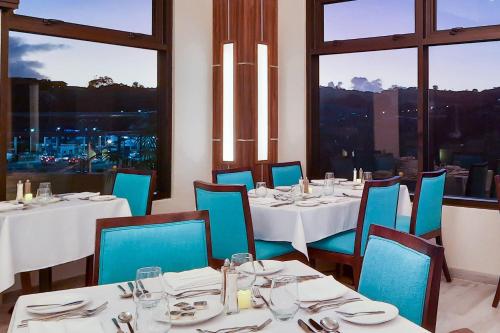 a restaurant with white tables and blue chairs and windows at Comfort Inn & Suites Tobago in Tobago Island