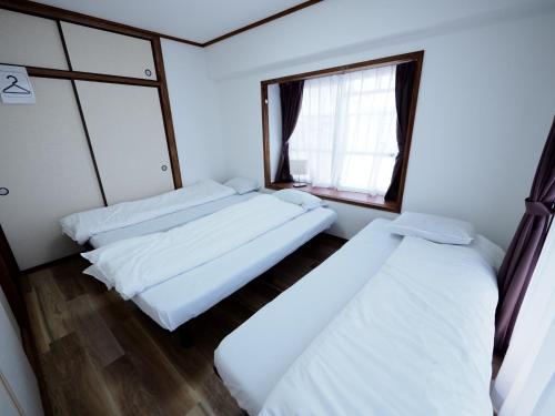 zwei Betten in einem Zimmer mit Fenster in der Unterkunft Living CUBE Beppu Station Annex / Vacation STAY 54919 in Beppu
