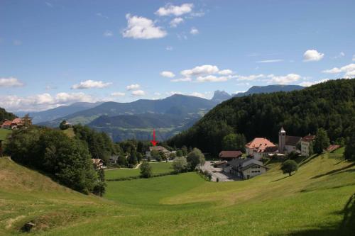 a green hillside with houses and mountains in the background at Sporthotel Spoegler in Collalbo