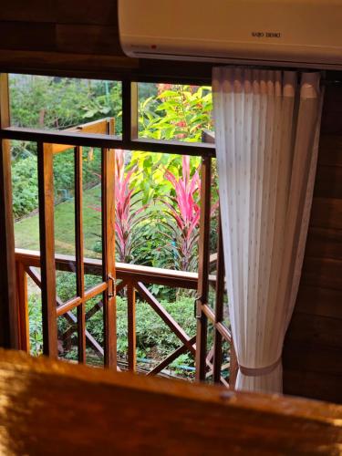 a window with a view of a garden at พลังความสุข รีสอร์ท ใจกลางเมืองพะเยา in Phayao