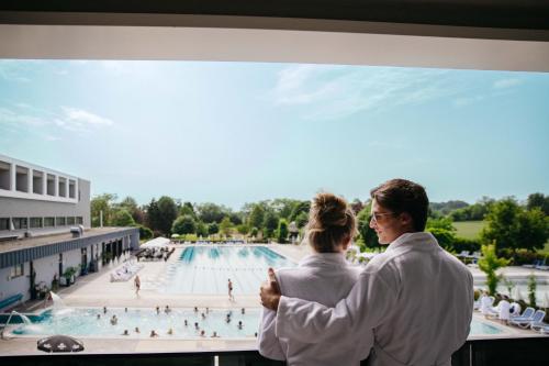 a man and a woman looking at a swimming pool at Hotel Vivat in Moravske Toplice