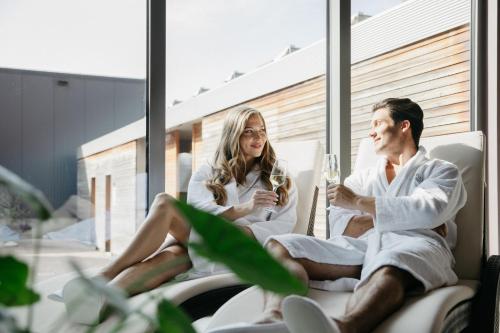 a man and woman sitting in towels and drinking wine at Hotel Vivat in Moravske Toplice