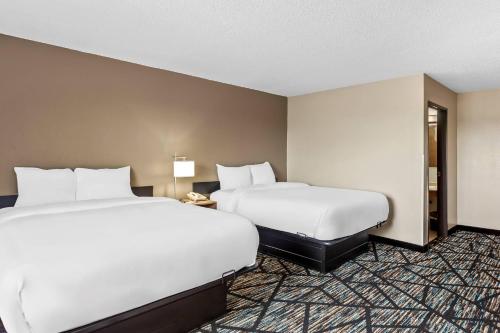 two beds in a hotel room with white sheets at Quality Inn & Suites Howe - Sturgis in Howe