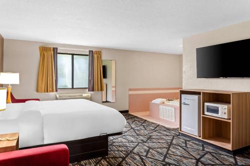 a hotel room with a bed and a flat screen tv at Quality Inn & Suites Howe - Sturgis in Howe