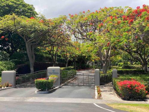 a gate in a park with trees with red flowers at Waikoloa Beach Condo in Waikoloa