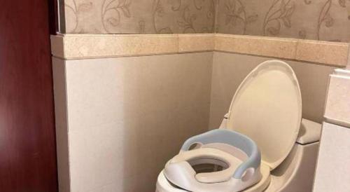 a bathroom with a white toilet with a blue seat at Hohhot Inner Mongolia Hotel in Hohhot