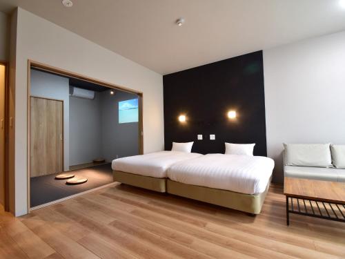 ein Schlafzimmer mit einem großen weißen Bett und einer Couch in der Unterkunft Rakuten STAY MOTEL Kujukurihama Katakai 203 1LDK with BBQ terrace in Kujukuri