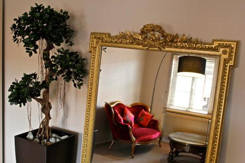 a room with a mirror and a red chair and a chair sidx sidx at Hôtel L'Auberge Alsacienne in Eguisheim