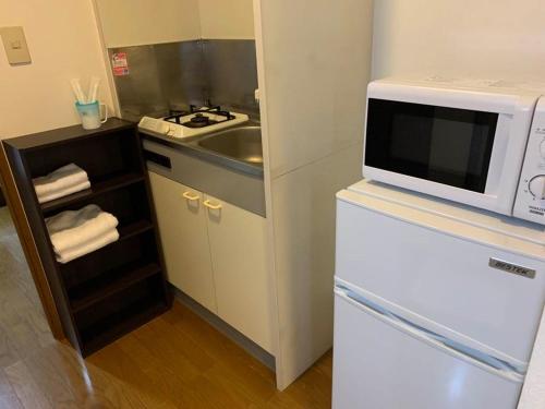 a kitchen with a microwave on top of a refrigerator at AO Dazaifu / Vacation STAY 61719 in Chikushino