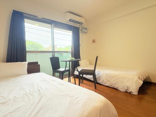 a room with two beds and a table and chairs at AO Dazaifu / Vacation STAY 61720 in Chikushino