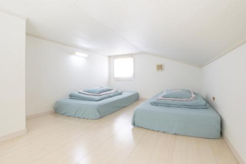 KamatachōにあるEtoile Soshigaya / Vacation STAY 62643の白い壁とウッドフロアの客室で、ベッド2台が備わります。