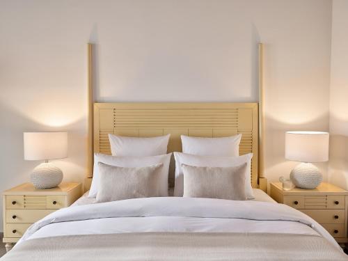 a bedroom with a large white bed with two lamps at Grecotel Marine Palace & Aqua Park in Panormos Rethymno