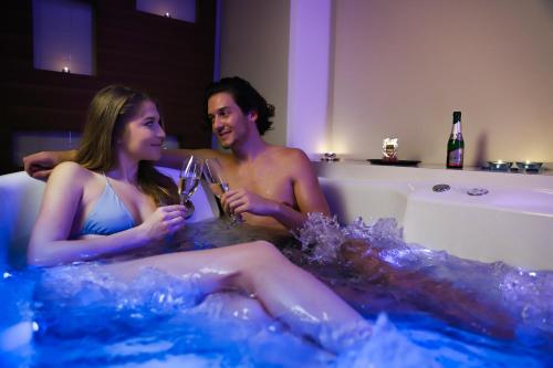 a man and woman sitting in a bath tub with wine glasses at Hotel Vivat in Moravske Toplice