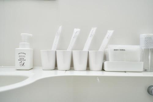 a row of white toiletries sitting on a bathroom counter at Rikyuan Kyoto Nishikyogoku room B in Kyoto