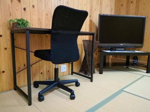a black office chair sitting next to a desk with a television at SYUkuhaku matuenosato / Vacation STAY 65782 in Matsue