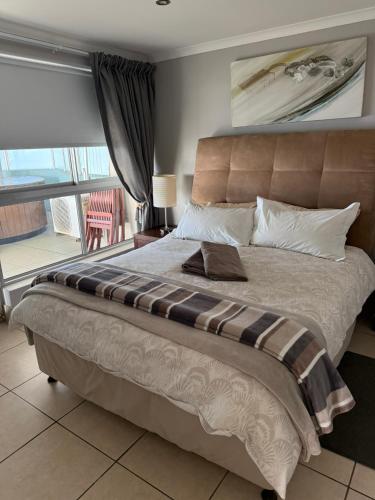 a bedroom with a large bed and a balcony at Nautica flat 401 in Mossel Bay