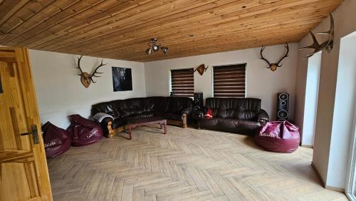 a living room with leather couches and a wooden ceiling at Pilsētas rezidence in Jēkabpils