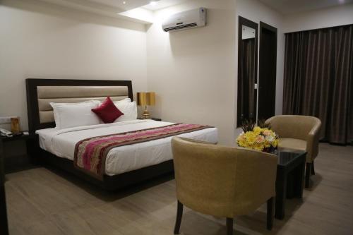 a hotel room with a bed and a chair at Hotel Central Palace in Dehradun