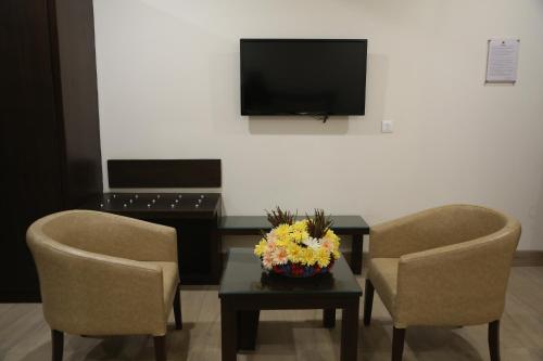 a room with two chairs and a table with a television at Hotel Central Palace in Dehradun