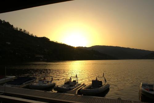 a group of boats docked in the water at sunset at Douro Hotel Porto Antigo in Cinfães