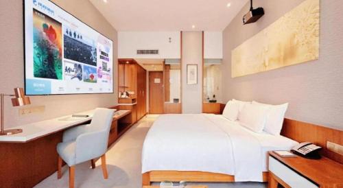 a hotel room with a large white bed and a desk at Deacon House Wuxi in Wuxi