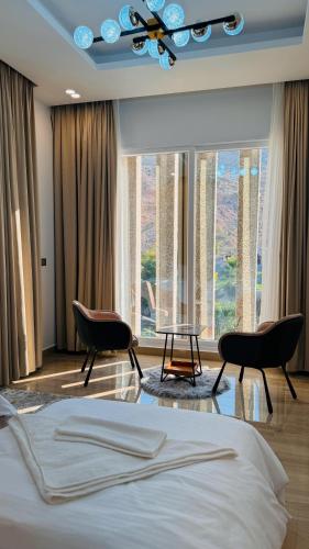 a bedroom with a bed and two chairs and a large window at جوهرة الرستاق السياحية in Far‘