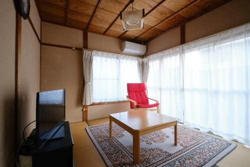 a living room with a table and a red chair at Ichiya no jikka / Vacation STAY 78859 in Shimosato