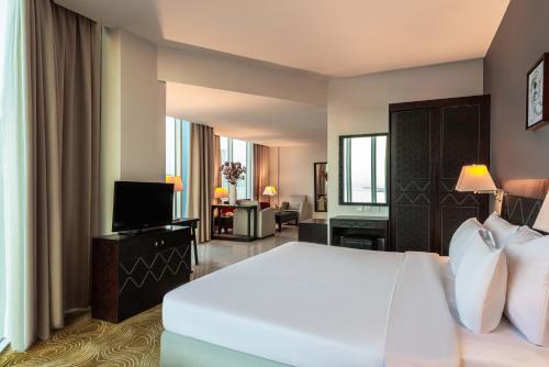 a hotel room with a bed and a television at Razana Hotel Al Jubail in Al Jubayl