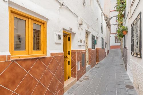 a narrow alley with a yellow door on a building at Alicia's House in Granada