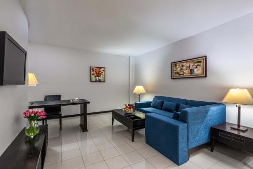 a living room with a blue couch and a desk at Razana Hotel Al Jubail in Al Jubayl