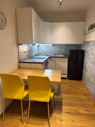 a kitchen with a wooden table and yellow chairs at Wilena Apartments in Villach