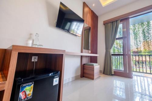 a living room with a tv and a large window at Puri Kaja House in Badung