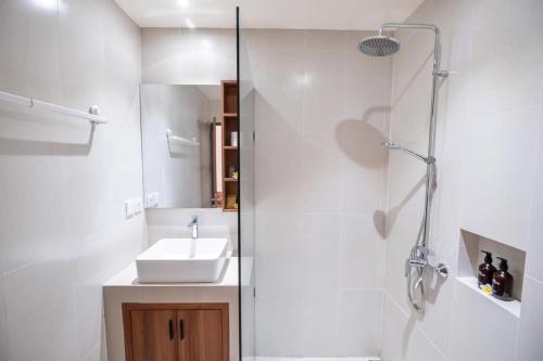 a white bathroom with a sink and a shower at Puri Kaja House in Badung