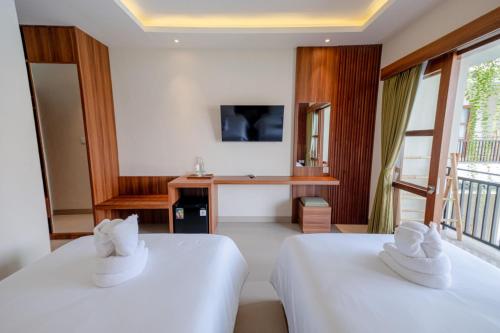 a hotel room with two beds and a desk at Puri Kaja House in Badung