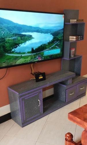 a flat screen tv sitting on a stand in a room at Moods Holiday Homes in Bulenga