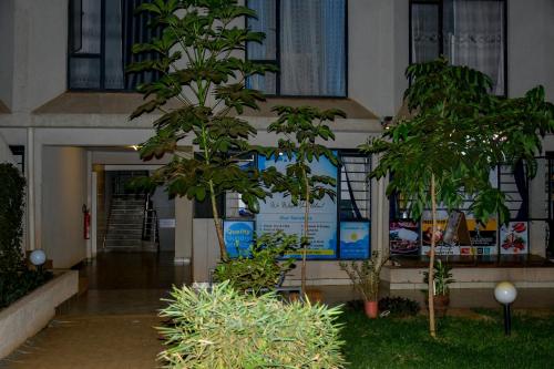 a building with two trees in front of it at Qwetu Luxelite Studio With Rooftop Pool in Nairobi