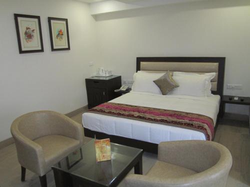 a bedroom with a bed and a chair and a table at Hotel Central Palace in Dehradun