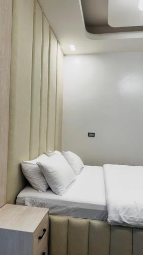 a bed with white pillows in a small room at جوهرة الرستاق السياحية in Far‘