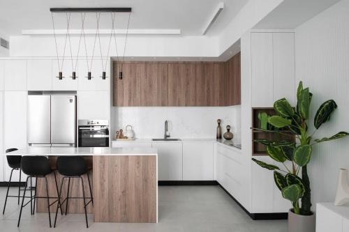 a kitchen with white cabinets and a island with bar stools at Prestige & Sea View 1BR with Parking TLV By Barnes in Tel Aviv