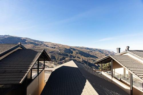 un groupe de bâtiments avec une montagne en arrière-plan dans l'établissement Moraima parking incluido, à Sierra Nevada