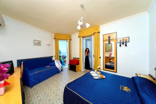 ein Wohnzimmer mit blauen Sofas und einer Frau im Spiegel in der Unterkunft Il Gattopardo Hotel Terme & Beauty Farm in Ischia