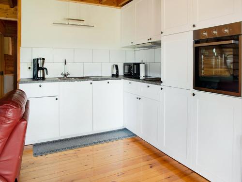 a white kitchen with white cabinets and a couch at Peaceful Retreat with Sauna in Fraiture