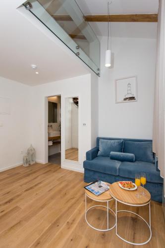 ein Wohnzimmer mit einem blauen Sofa und einem Tisch in der Unterkunft Bifora Heritage Hotel in Trogir