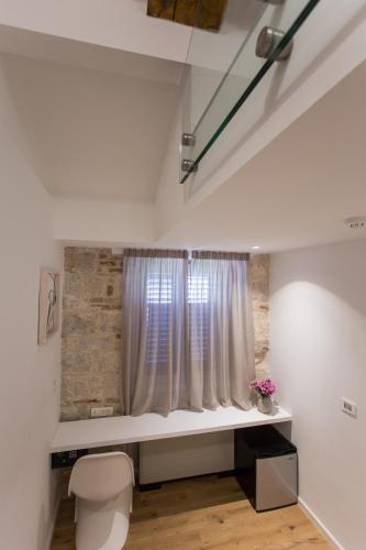 a bathroom with a toilet and a window at Bifora Heritage Hotel in Trogir