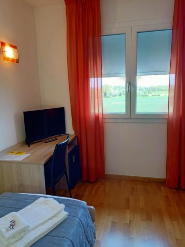 a room with a bed and a desk and a window at Al Cavaliere in Pordenone
