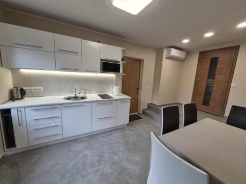 a kitchen with white cabinets and a table with chairs at A&G SODYBA APARTAMENT WITH a TERRACE 